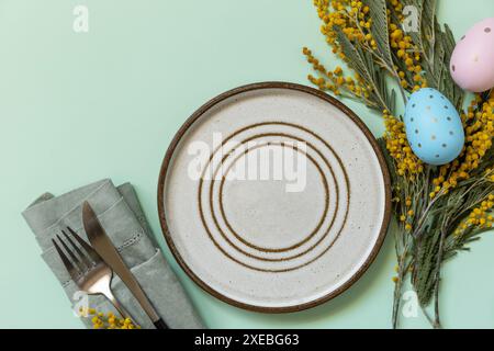 Table setting for Easter dinner with easter eggs and mimosa on a pastel background Stock Photo