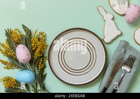 Table setting for Easter dinner with easter eggs and mimosa on a pastel background. Stock Photo