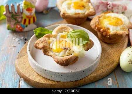 Scrambled eggs in puff pastry with cheese and bacon. Easter breakfast on a festive table. Stock Photo