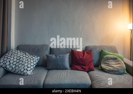 Modern grey fabric sofa with pillows and lighting lamp in living room Stock Photo