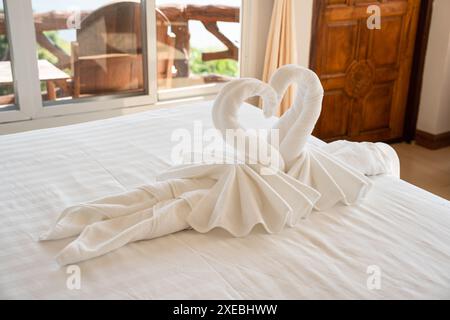 Folded towels shaped like couple swan on the bed in the hotel Stock Photo