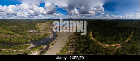 Aerial view of Paradise Dam on the Burnett River surrounded by a hoop pine forest under a cloudy sky Stock Photo