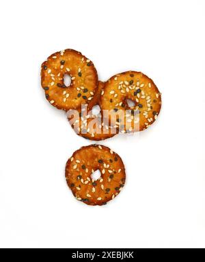 Salted round pretzels with black and white sesame isolated on white. Cracker chips with sea salt isolated on white background. Round shape appetizers. Stock Photo