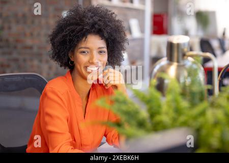 Smiling African American businesswoman in casual attire sitting at desk in office Stock Photo