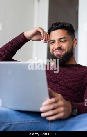 Smiling man using laptop while relaxing at home, enjoying leisure time Stock Photo