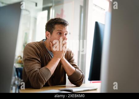 Portrait of a disappointed man programmer looking stressed out while working on a computer code Stock Photo