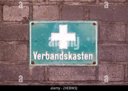 Writing on the wall of an old metallurgical plant in Germany - first aid kit. Green plate with a white cross and inscription in German. Stock Photo