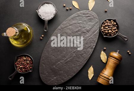 Various spices and an empty black board on the table. Salt, pepper and olive oil Stock Photo