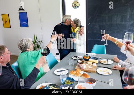 Elderly Couple Kissing at Family Gathering Toast Stock Photo