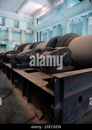 Interior view of an old hydroelectric plant, displaying rusty, gigantic mechanical gears and equipment in disuse. Stock Photo