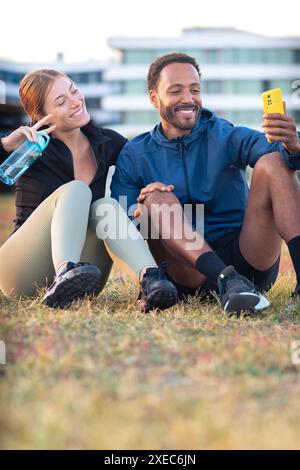 Young couple taking a selfie with their smartphone ready to exercise.Vertical Stock Photo