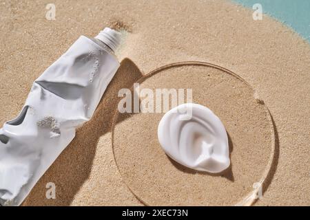 A tube of moisturizing sunscreen and a smear on a sandy background. Stock Photo
