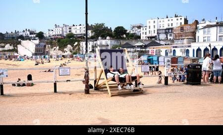 male tourists sitting on a giant deckchair,broadstairs seaside town,thanet,kent,uk june 2024 Stock Photo