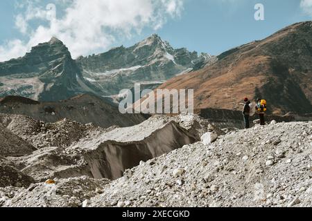 Two trekkers trekking in Himalayas mountains through Chola glacier pass to Gokyo Ri. Nepalese male guide leading tourist client in Sagarmatha national Stock Photo