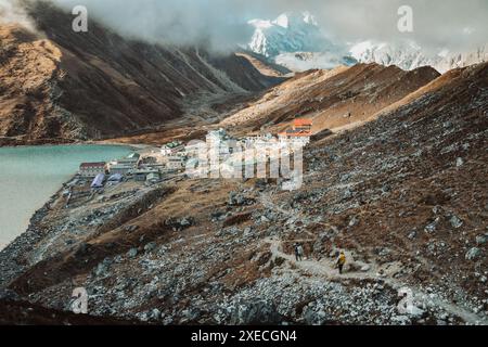 Two trekkers trekking in Himalayas mountains arrive to Gokyo Ri village. Nepalese male guide leading tourist client in Sagarmatha national park offici Stock Photo