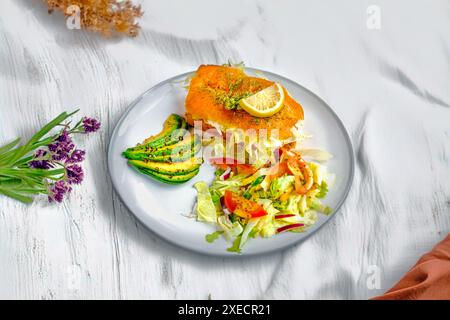 A gourmet plate featuring a fresh salmon fillet topped with a lemon slice, served with sliced avocado and a vibrant mixed vegetable salad. Stock Photo