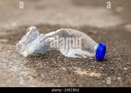 Plastic bottle is laying on the ground, broken and discarded Stock Photo