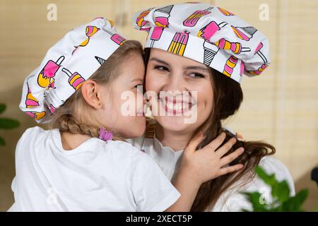 While eating home-made pizza, a five-year-old daughter hugs her mother warmly, thus reciprocating her mother's love for her chil Stock Photo