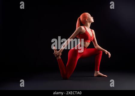 Young woman practicing yoga against black background Stock Photo