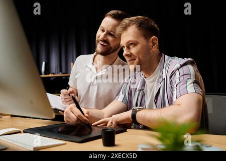 Two men in casual attire, happily collaborating on a project using a laptop at a desk. Stock Photo