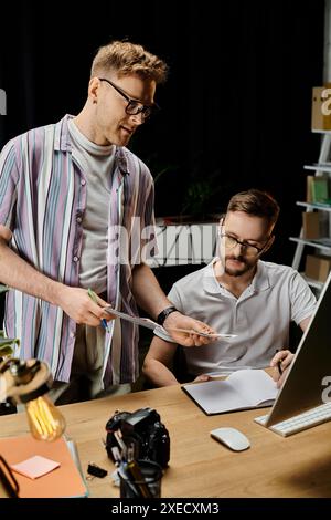 Two men standing, collaborating in front of a laptop computer. Stock Photo