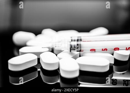 Medical Concept: White Oval Pills and Syringe on a Reflective Surface, Focus on Healthcare and Prescription Practices, prescription drugs, fentanyl Stock Photo