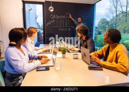 Motivated Startup Team in Strategy Session by Chalkboard with Growth Concepts Stock Photo