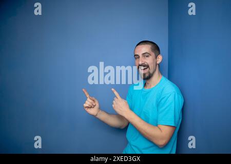 Young man pointing empty space using hands and fingers, isolated over blue background Stock Photo
