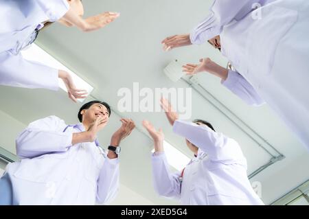A delighted doctor team enjoying achievement in a hospital setting with clap hands. Stock Photo