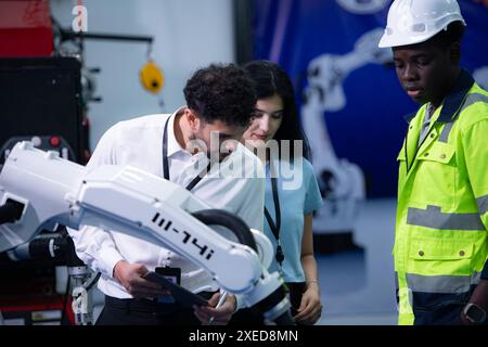 Technicians are introducing industrial hand robots to businessperson of factory industry who will use them in large-scale comple Stock Photo