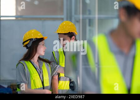 Portrait of young male factory worker wearing a hard hat looking at a computer screen used to control production. Stock Photo