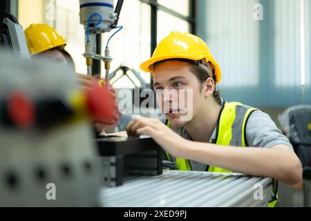 Portrait of a technician young male worker in a factory working on a small robot machine Stock Photo