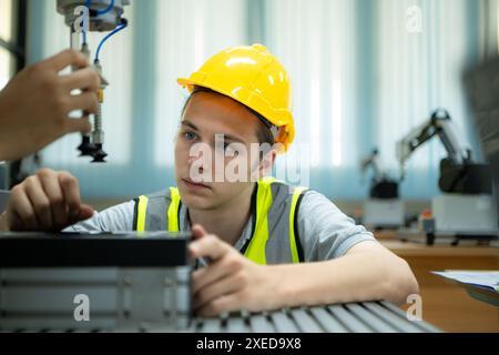 Portrait of a technician young male worker in a factory working on a small robot machine Stock Photo