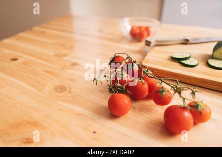 Slicing cherry tomatoes and cucumbers on a wooden cutting board Stock Photo
