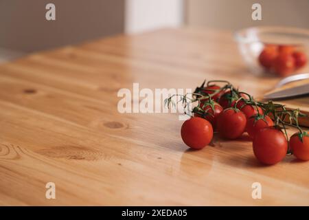 Slicing cherry tomatoes and cucumbers on a wooden table Stock Photo