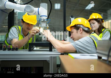 Group of engineers and technicians learning the technology to control hand robots for industrial usage. Stock Photo