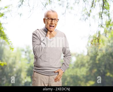 Elderly man with hay fever coughing in a park Stock Photo