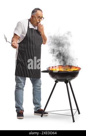 Shocked man standing next to a burning bbq isolated on white background Stock Photo