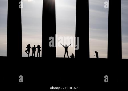 Silhouette of young people in different poses between columns of National Monument of Scotland on the Calton Hill in city of Edinburgh, Scotland, UK. Stock Photo