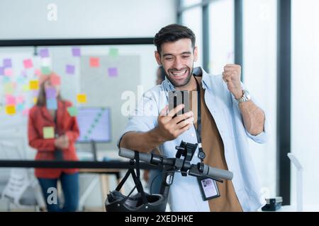 Portrait of smiling businessman talking on mobile phone while colleague using scooter in office Stock Photo