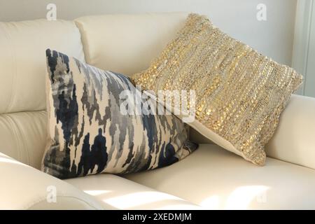 Leather weave cushion and velvet blue and gray camouflage printed cushion on top of a white love seat sofa Stock Photo