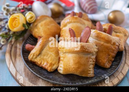 Buns in the form of an Easter rabbit and colored eggs on a wooden table. Stock Photo