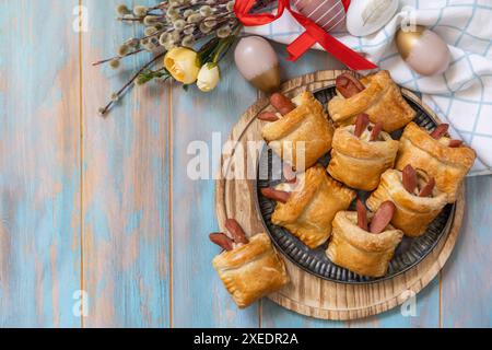 Buns in the form of an Easter rabbit and colored eggs on a wooden table. Stock Photo