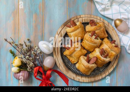Buns in the form of an Easter rabbit and colored eggs on a wooden table. Stock Photo