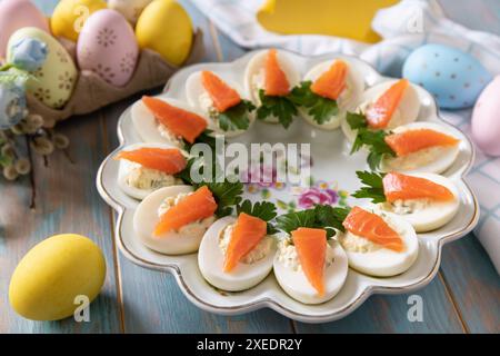 Stuffed eggs with cheese and salted salmon in the form of a carrot on a wooden table. Stock Photo