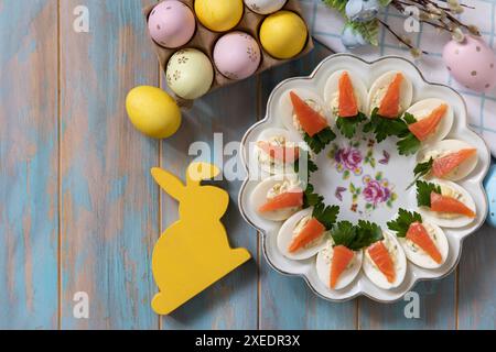 Stuffed eggs with cheese and salted salmon in the form of a carrot on a wooden table. Stock Photo
