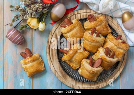 Buns in the form of an Easter rabbit and colored eggs on a wooden table. Stock Photo