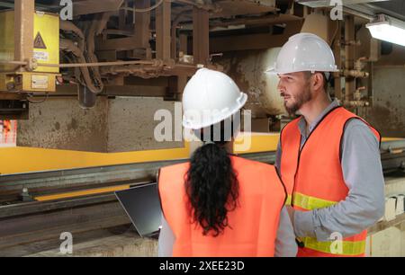 Male and female engineers work together in an electric repair station. Inspecting the undercarriage of electric train that are b Stock Photo