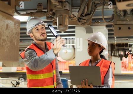 Male and female engineers work together in an electric repair station. Inspecting the undercarriage of electric train that are b Stock Photo