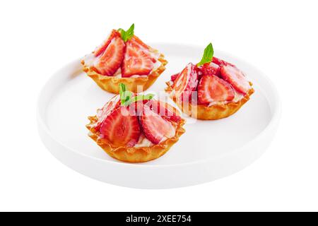 Tartlets with custard, strawberries and mint served on white plate Stock Photo
